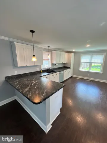 a kitchen with a stove a sink and a wooden floor