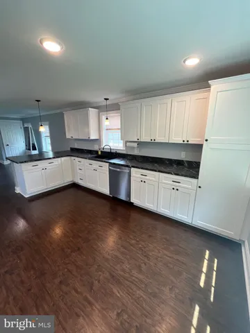 a kitchen with granite countertop a stove top oven a sink a counter space and cabinets