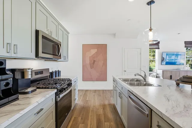 a kitchen with stainless steel appliances granite countertop a sink a stove oven a counter space and cabinets