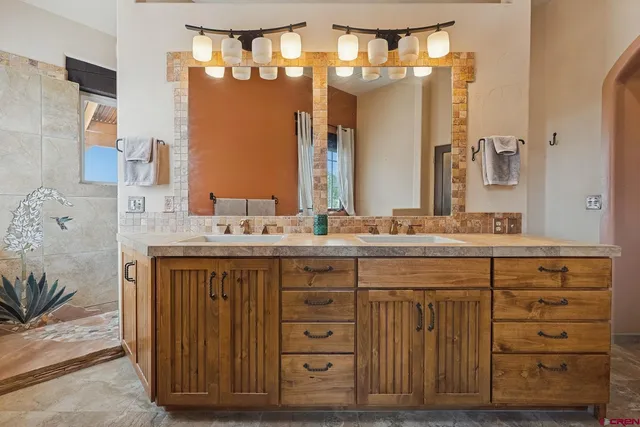 a bathroom with a granite countertop double vanity sink and a mirror