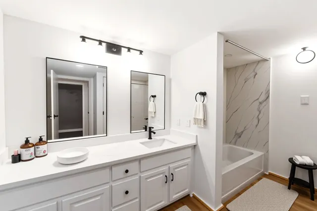 a bathroom with a tub sink and mirror