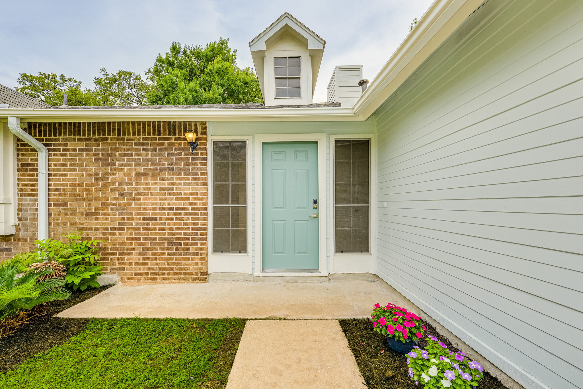 4815 Transit Circle Austin, TX 78727 - Photo 2 of 35 Cute front entry featuring a cheerful light turquoise door, traditional brick façade, horizontal siding, and a charming overhead dormer.