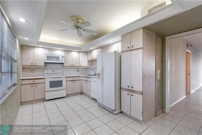 3520 Oaks Way, Unit 607 Pompano Beach, FL 33069 - Photo 12 of 31 a kitchen with white cabinets a sink and white appliances