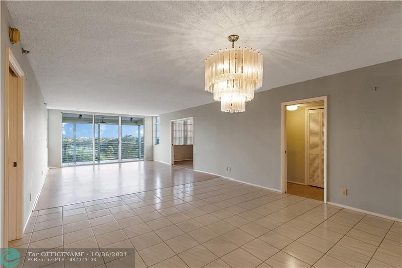 3520 Oaks Way, Unit 607 Pompano Beach, FL 33069 - Photo 7 of 31 a view of empty room with wooden floor and chandelier