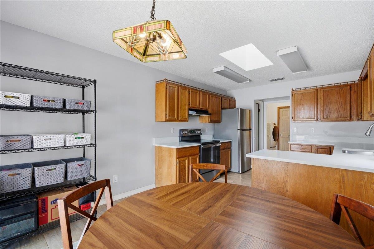 204 Queen Road St. Augustine, FL 32086 - Photo 14 of 55 Kitchen with light countertops, black electric range, wood finish cabinets, freestanding refrigerator, and hanging light fixtures