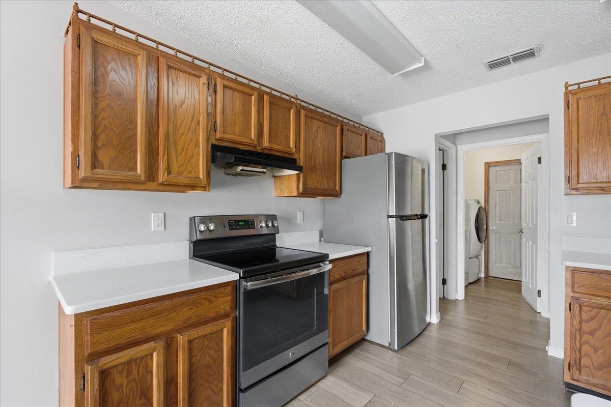 204 Queen Road St. Augustine, FL 32086 - Photo 16 of 55 Kitchen featuring stainless steel appliances, wood finish cabinets, light countertops, a textured ceiling, and light wood-style floors