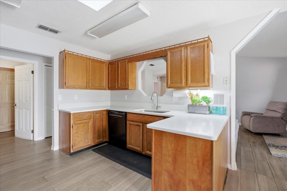 204 Queen Road St. Augustine, FL 32086 - Photo 17 of 55 Kitchen featuring light countertops, light wood-type flooring, dishwasher, a textured ceiling, and a peninsula