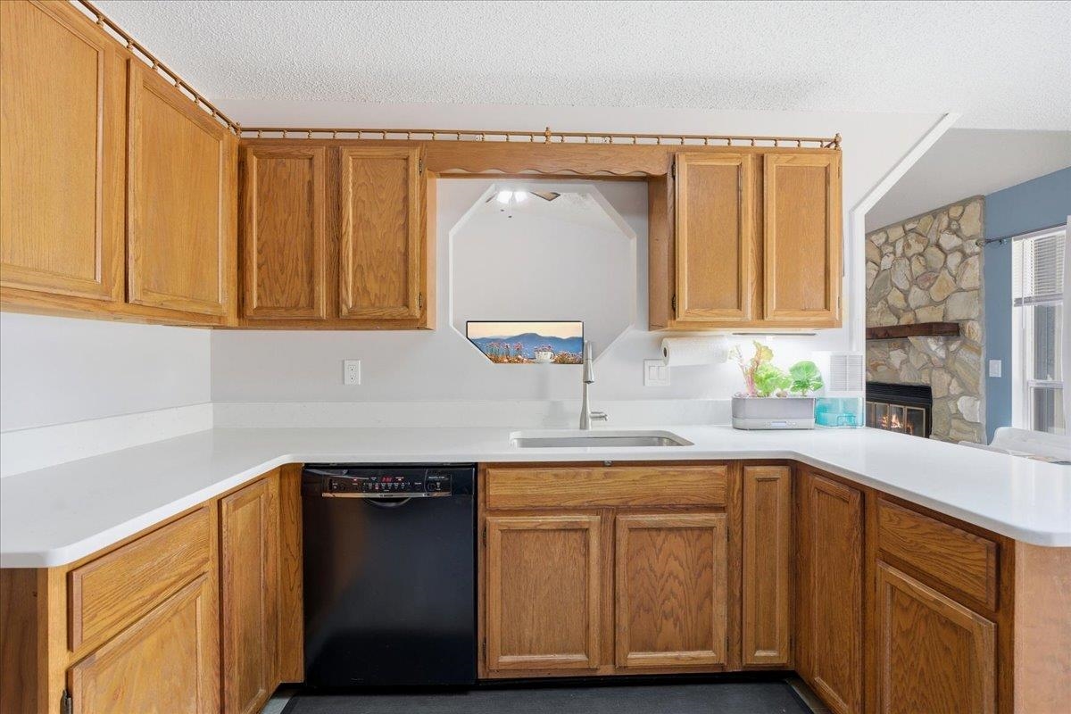 204 Queen Road St. Augustine, FL 32086 - Photo 18 of 55 Kitchen with dishwasher, wood finish cabinets, a fireplace, and a textured ceiling