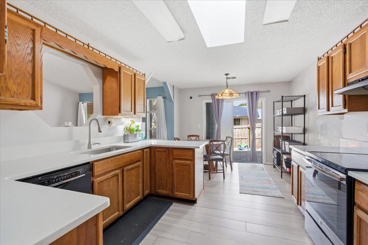 204 Queen Road St. Augustine, FL 32086 - Photo 19 of 55 Kitchen with electric range, wood finish cabinetry, a textured ceiling, a peninsula, and decorative light fixtures