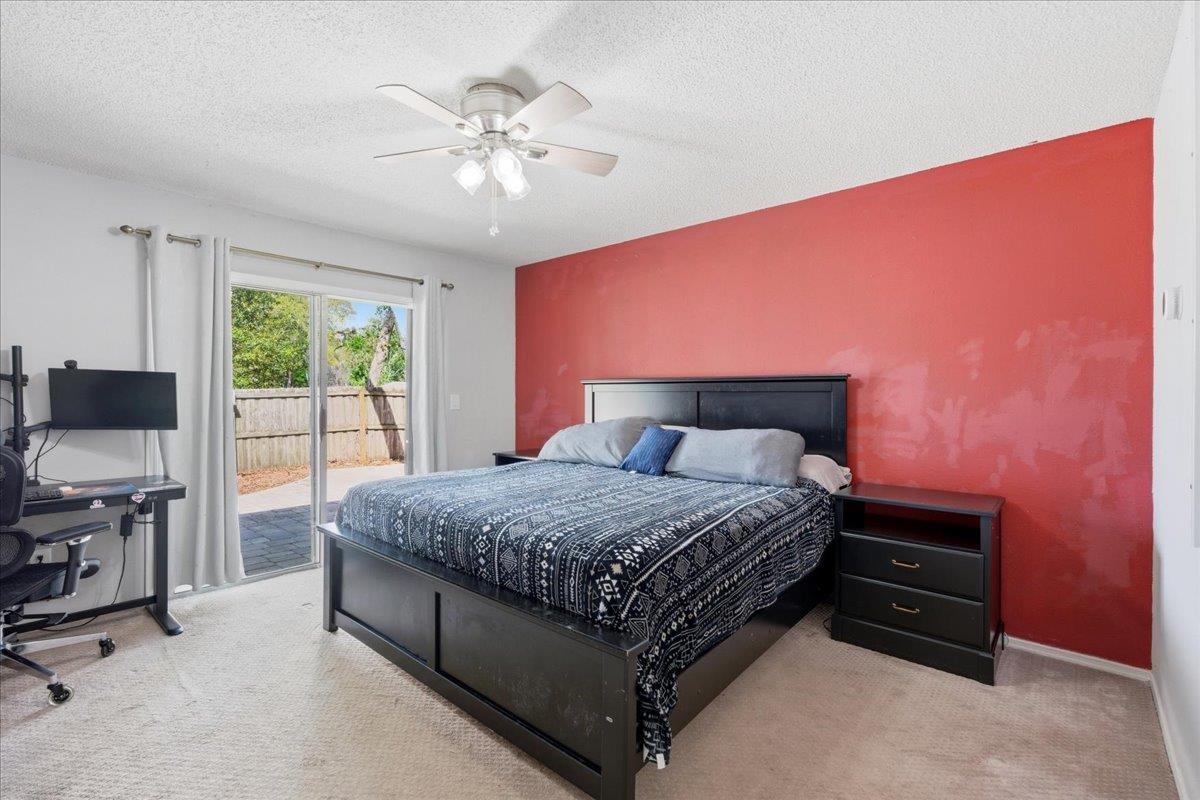204 Queen Road St. Augustine, FL 32086 - Photo 20 of 55 Bedroom featuring access to exterior, light colored carpet, a ceiling fan, a textured ceiling, and an accent wall