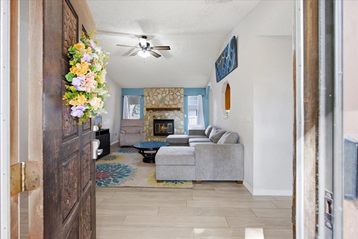 204 Queen Road St. Augustine, FL 32086 - Photo 7 of 55 Living room featuring a textured ceiling, light wood finished floors, ceiling fan, and a fireplace