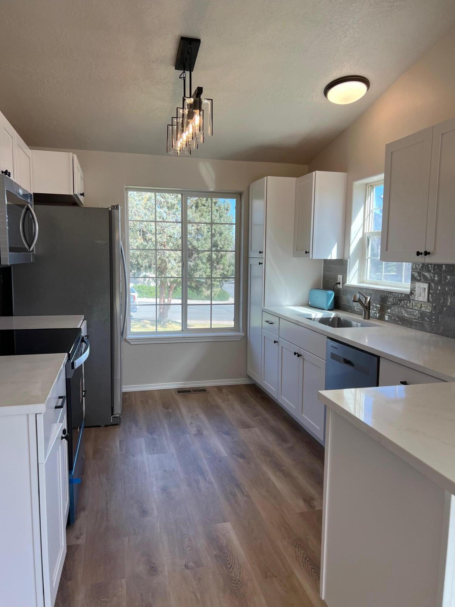 629 Deer Ridge Court Madras, OR 97741 - Photo 8 of 39 a kitchen with granite countertop a stove a sink dishwasher and a refrigerator with wooden floor