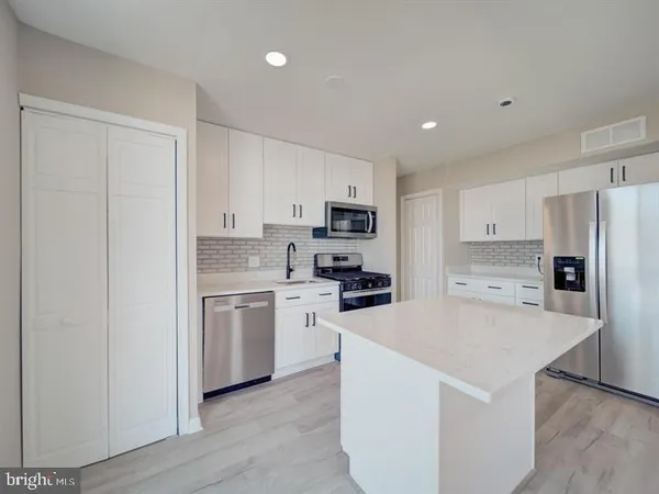 a kitchen with a refrigerator a stove top oven a sink and cabinets