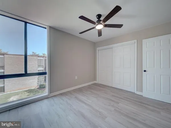 an empty room with wooden floor fan and windows