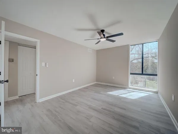a view of empty room with wooden floor and ceiling fan