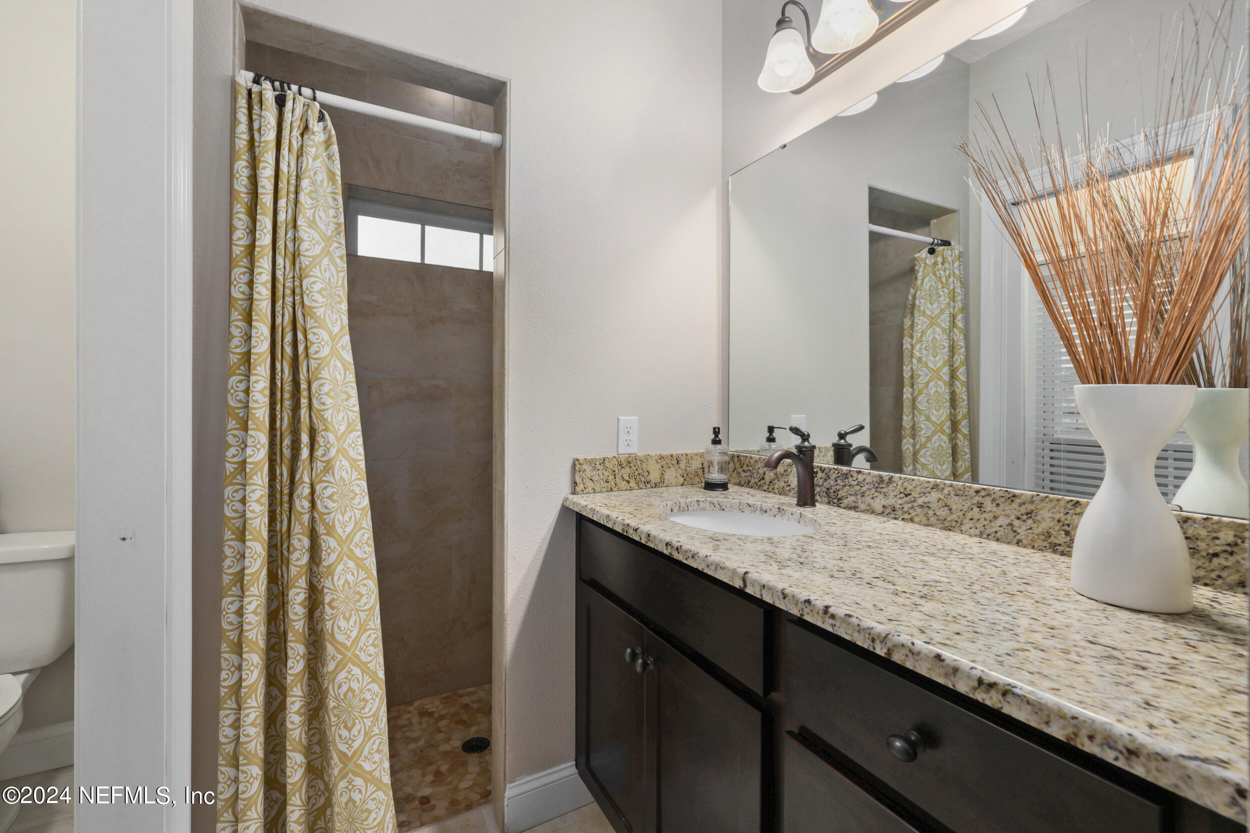 55278 Bartram Trail Callahan, FL 32011 - Photo 38 of 88 a bathroom with a granite countertop sink and a mirror