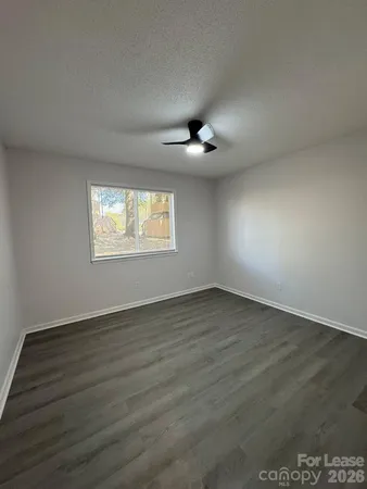 an empty room with wooden floor chandelier and windows