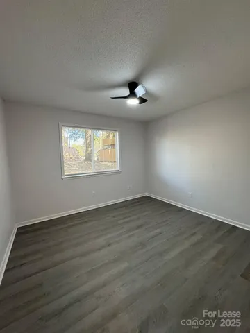 an empty room with wooden floor chandelier and windows