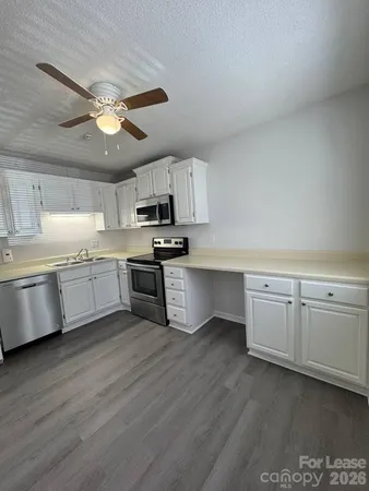 a kitchen with stainless steel appliances white cabinets a sink a stove a microwave and wooden floors