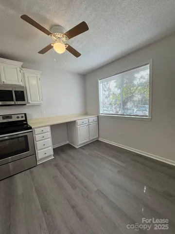 an empty room with wooden floor cabinet and windows