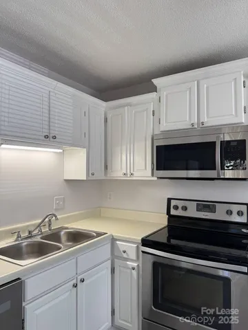 a kitchen with white cabinets and stainless steel appliances