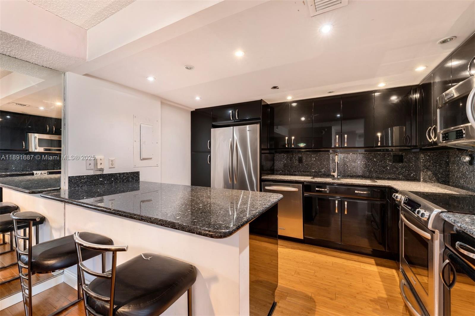 1000 Quayside Terrace, Unit PH9 Miami, FL 33138 - Photo 11 of 27 a kitchen with stainless steel appliances granite countertop a sink a stove a microwave a refrigerator and chairs