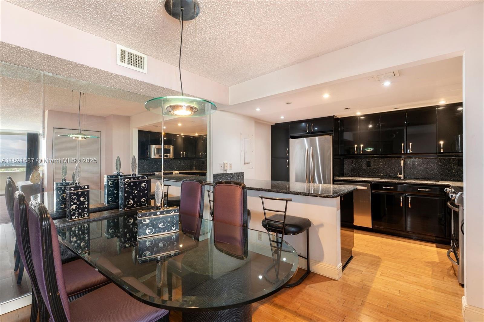 1000 Quayside Terrace, Unit PH9 Miami, FL 33138 - Photo 12 of 27 a kitchen with stainless steel appliances kitchen island granite countertop a stove a refrigerator a kitchen island a dining table and chairs