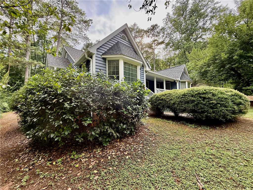 A classic exterior with charming bay windows, wrapped in verdant shrubbery, offers private, tree-lined living.