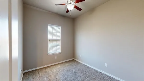 an empty room that has a window and a chandelier fan