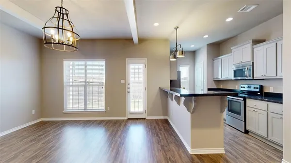 a kitchen with stainless steel appliances granite countertop a stove a sink dishwasher a refrigerator and a dining table with wooden floor