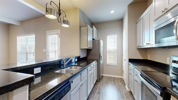 a kitchen with stainless steel appliances granite countertop a sink a stove cabinets counter space and a window