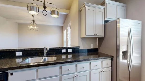 a kitchen with granite countertop stainless steel appliances a refrigerator a sink and cabinets