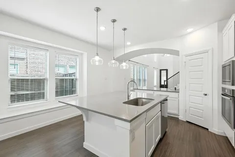 a kitchen with stainless steel appliances granite countertop a sink a stove and a wooden floors