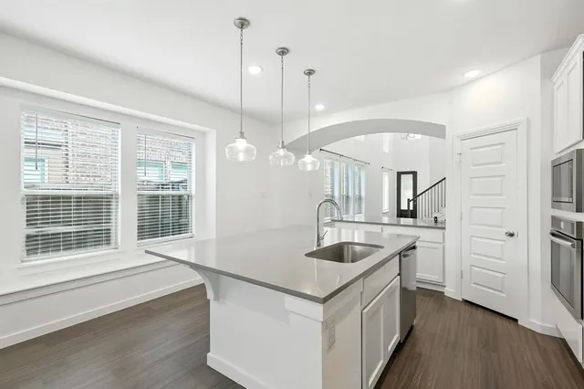 a kitchen with stainless steel appliances granite countertop a sink a stove and a wooden floors