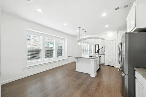 a kitchen with stainless steel appliances granite countertop a refrigerator a sink dishwasher a stove and white countertops with wooden floor