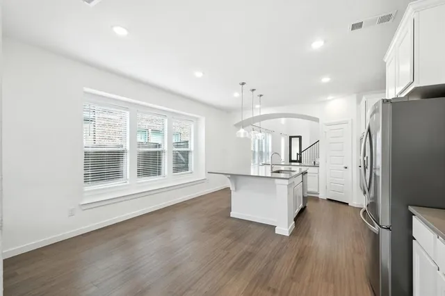 a kitchen with stainless steel appliances granite countertop a refrigerator a sink dishwasher a stove and white countertops with wooden floor