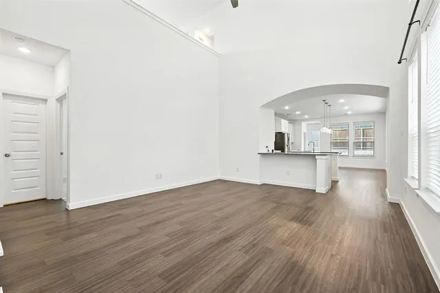 an empty room with wooden floor and kitchen view