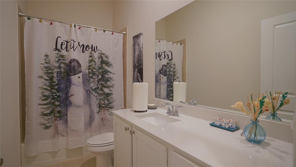 1101 Ginger Road Aubrey, TX 76227 - Photo 8 of 16 a bathroom with a granite countertop sink a toilet and shower curtain