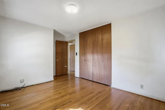 a view of an empty room with wooden floor and closet
