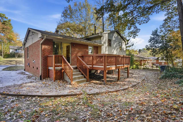 a view of a wooden house with a yard and sitting area