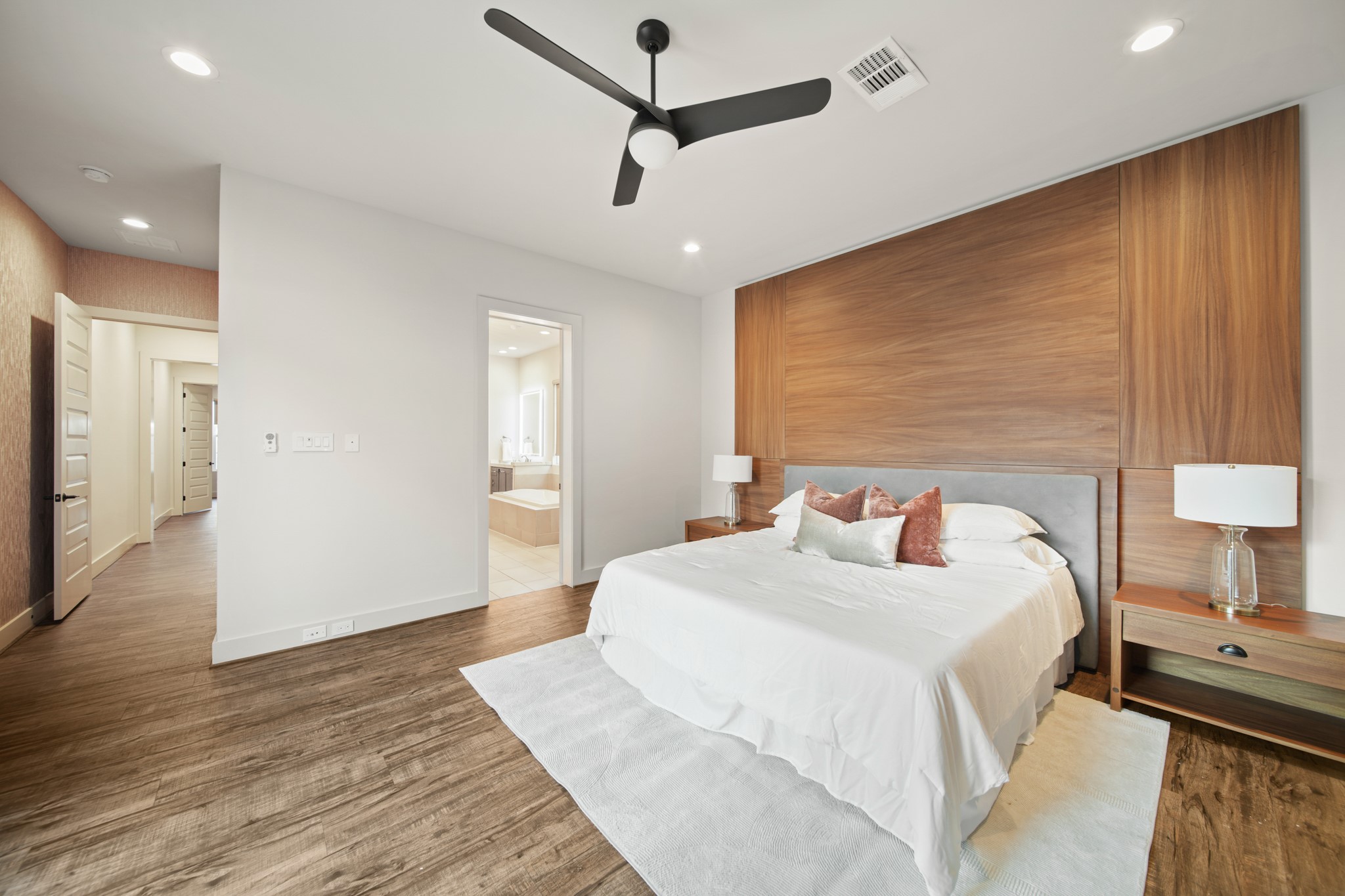 5434 Windswept Lane Houston, TX 77056 - Photo 21 of 45 This grand primary bedroom showcases high ceilings, a striking wood accent wall, a contemporary black fan, and abundant space for relaxation.