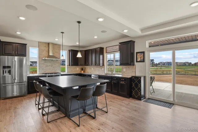 a kitchen with granite countertop a refrigerator a stove a sink a dining table and chairs with wooden floor