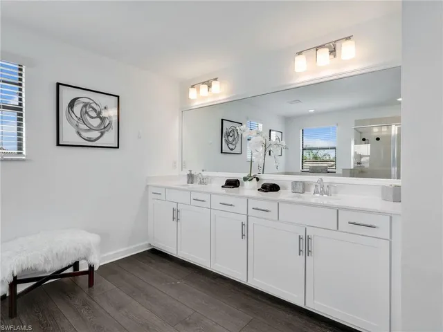 a spacious bathroom with 2 sink flowerpot and a mirror