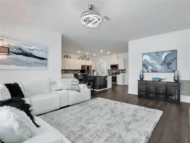a living room with furniture kitchen view and a wooden floor
