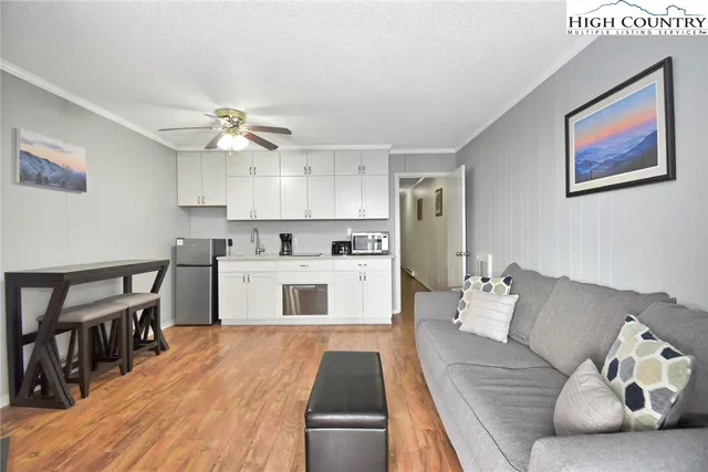 a kitchen with stainless steel appliances granite countertop a stove a sink dishwasher and white cabinets with wooden floor