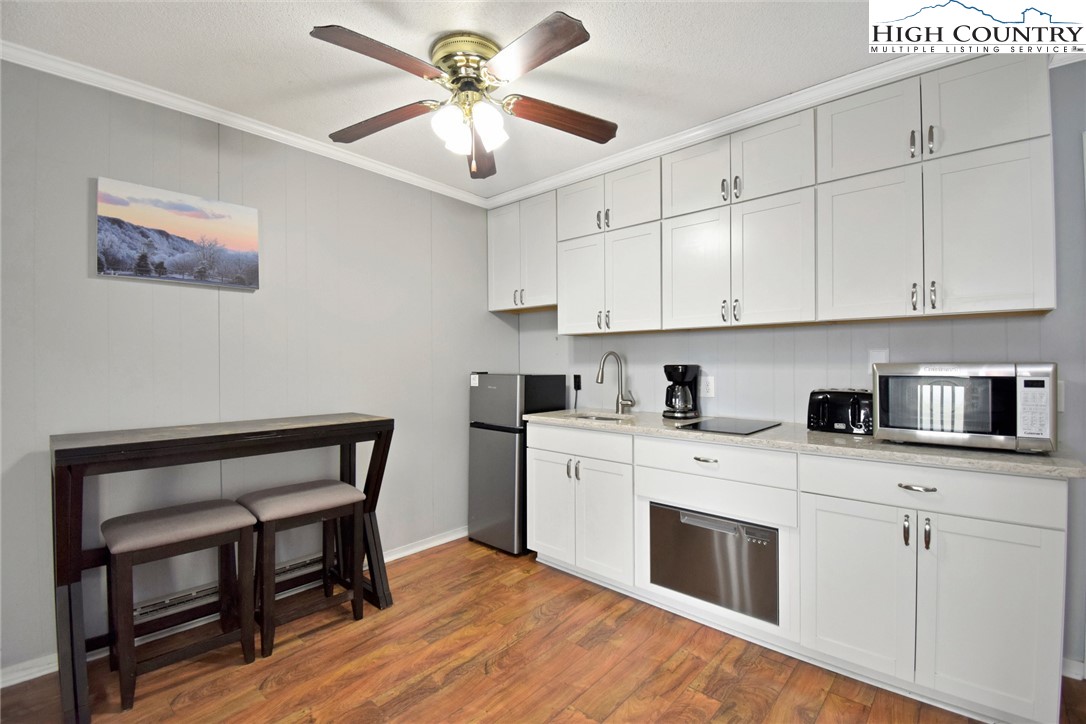 301 Pinnacle Inn Road, Unit 3130 Beech Mountain, NC 28604 - Photo 19 of 41 a kitchen with stainless steel appliances granite countertop a stove a sink dishwasher and white cabinets with wooden floor