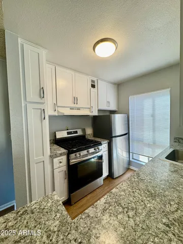 a kitchen with stainless steel appliances granite countertop a stove a sink and a refrigerator