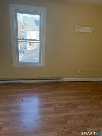 an empty room with wooden floor cabinet and windows