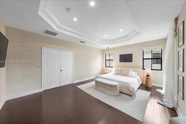 a spacious bathroom with a granite countertop double vanity sink a mirror a bathtub and a window