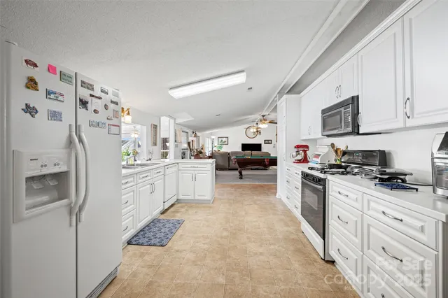 a kitchen with stainless steel appliances granite countertop a refrigerator sink stove and white cabinets